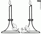 Due candele accese in candelabri decorati con foglie di agrifoglio